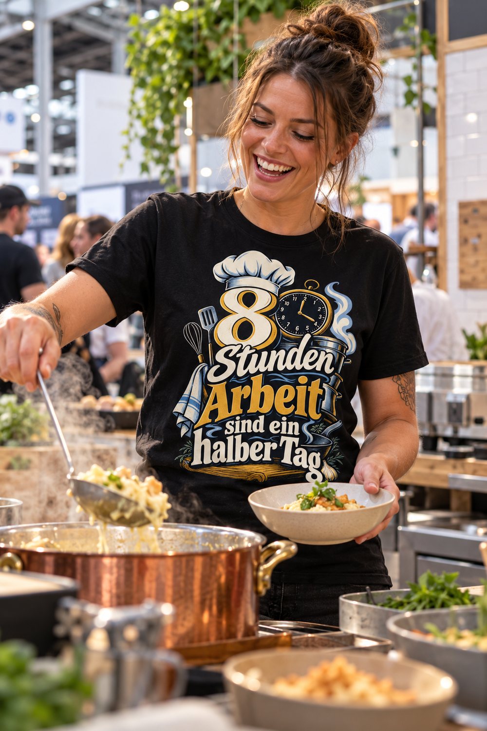 KI-Szenenbild: Köchin richtet auf einer Food-Messe am Live-Cooking-Buffet aus einem Kupfertopf an, schwarzes Shirt mit dem Motiv „8 Stunden Arbeit sind ein halber Tag“